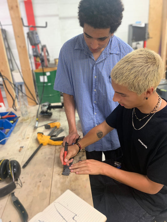 Two students marking blade designs on tool steel during a knife-making workshop at Oldboy Metal Co., Toronto.