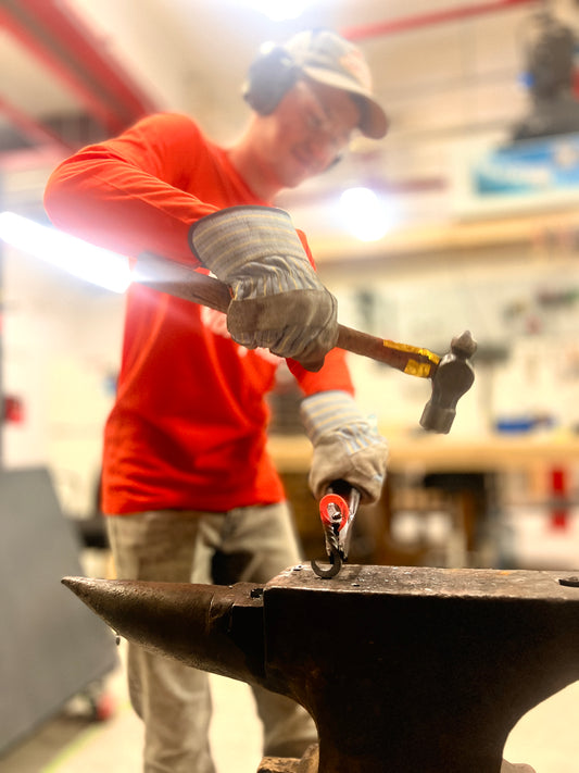 Participant forging an S-hook on the anvil during the one-hour blacksmithing taster session at Oldboy Metal Co. in Toronto.