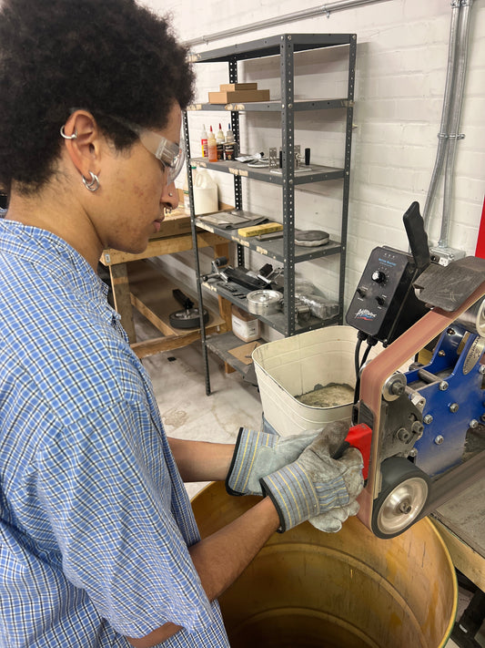 Participant sharpening a hand-forged blade on a belt grinder during one-day blacksmith’s knife workshop at Oldboy Metal Co. in Toronto.
