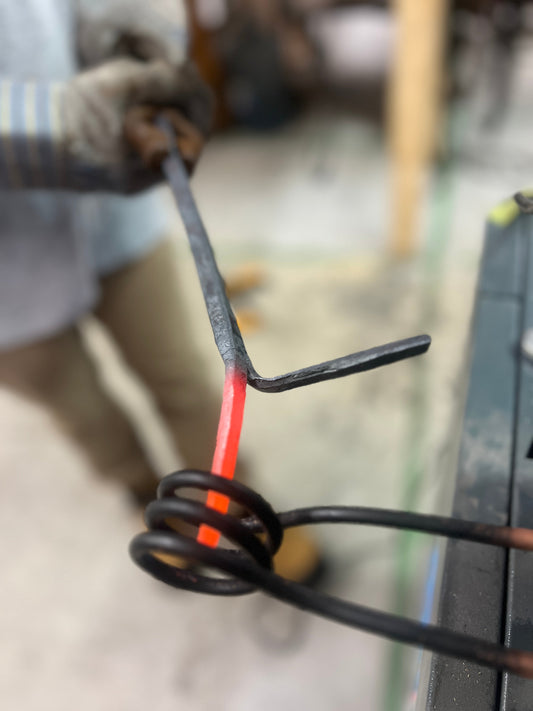 Close-up of a glowing red-hot steel bar being heated in an induction coil during a blacksmithing workshop at Oldboy Metal Co.