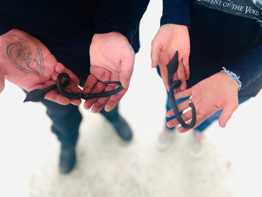 Two participants holding hand-forged wall hooks made during beginner blacksmithing workshop at Oldboy Metal Co. in Toronto.