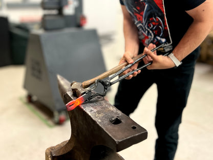 Forging a red-hot steel bottle opener on the anvil during beginner blacksmithing workshop at Oldboy Metal Co. in Toronto