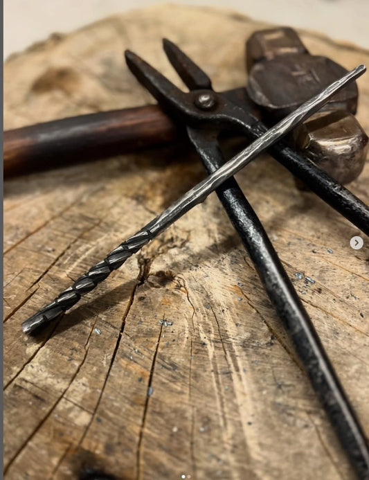 Beginner-friendly blacksmithing project from kids wand forging class in Toronto, hand-forged twisted steel wand on wooden anvil block